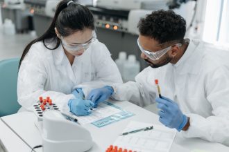 Pesquisadores usando equipamentos de proteção analisam dados em um laboratório.