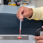 Técnico de laboratório utiliza uma micropipeta para realizar medições precisas em um ambiente de pesquisa.