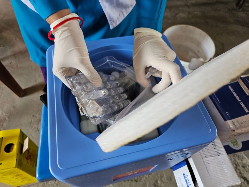 Profissional de saúde usando luvas manuseia frascos e amostras em um laboratório.